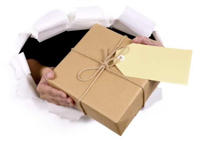 A person's hands hold a wrapped package with a blank tag emerging from a hole.